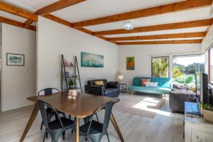 a living room with a wooden table and chairs at Onetangi Beach Retreat - Waiheke Holiday Home in Onetangi
