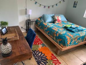 a living room with a bed and a table at Manta Soul Tiki Cottage in Kealakekua