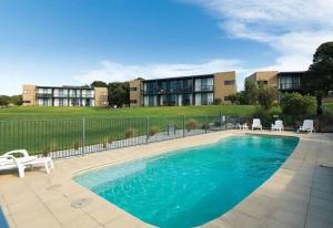 a swimming pool with chairs and a building in the background at Luxury 1BR Apartment - Golf & Hot Springs Retreat! in Fingal