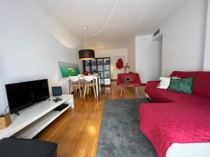 a living room with a red couch and a tv at Apartamento do Atlântico in Ponta Delgada