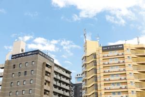 HOTEL Third Place Hakata في فوكوكا: عمارتين طويلتين امام السماء الزرقاء