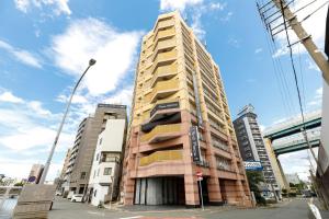 un edificio alto en una calle de la ciudad con edificios en HOTEL Third Place Hakata en Fukuoka