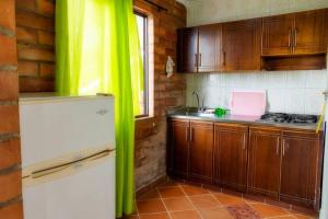 マリニリャにあるFinca La Piscina, disfrute totalの木製キャビネットと緑のカーテン付きのキッチン