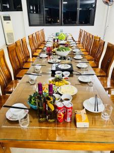a long wooden table with plates of food and drinks at Hồng Anh 2 Hotel in Ha Long