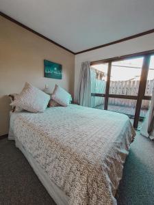 a bedroom with a large bed and a large window at Evergreen Escape Hokitika in Hokitika
