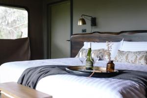 a tray with wine glasses and wine bottles on a bed at Peninsula Hot Springs in Fingal