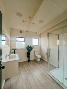 a bathroom with a shower and a sink and a toilet at Evergreen Escape Hokitika in Hokitika