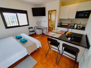 Habitación con cocina y mesa con sillas. en Casita rural de Tamara, en Coín