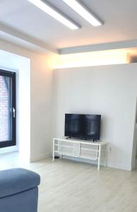 a living room with a flat screen tv on a white wall at Elle House in Jeonju