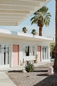 a white house with a palm tree in front of it at Miracle Manor Boutique Hotel & Spa in Desert Hot Springs