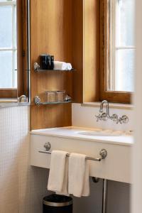 een badkamer met een wastafel, een spiegel en handdoeken bij Sydney Harbour Hotel in Sydney