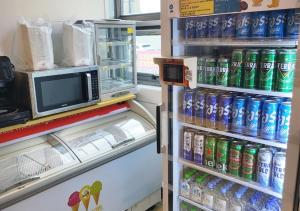 um frigorífico cheio de latas de refrigerante e um micro-ondas em Jeju Parkside Tourist Hotel em Jeju