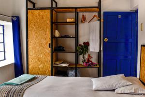 a room with a bed and a blue door and shelves at Saqray Hostel in Cusco