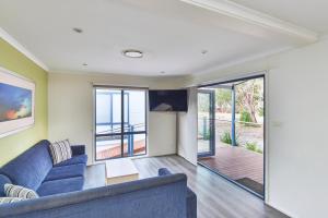 a living room with a blue couch and sliding glass doors at NRMA Ocean Beach Holiday Resort in Umina
