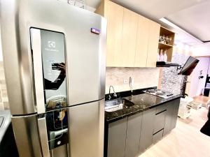 a stainless steel refrigerator in a kitchen with a person taking a picture at Exclusivo Apartastudio Zona Norte de Bogota in Bogotá