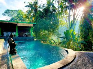 a woman sitting in front of a swimming pool at Dupa Ubud in Ubud