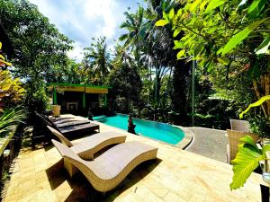 a swimming pool with chairs and a person in the background at Dupa Ubud in Ubud