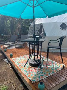 a table and chairs under an umbrella on a deck at Manta Soul Jungle Geodome in Kealakekua
