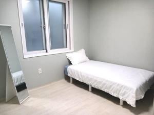 a small room with a bed and a window at Elle House 2 in Jeonju