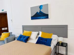 Schlafzimmer mit einem Bett mit gelben und blauen Kissen in der Unterkunft Casa Chiara Italia luxury central free parking in Neapel