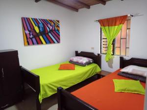 a room with two beds and a painting on the wall at EL RETORNO in Marinilla