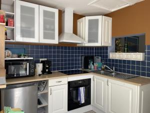 eine Küche mit weißen Schränken und einer blau gefliesten Wand in der Unterkunft Maison Plouhinec, 2 pièces, 4 personnes - FR-1-397-76 in Plouhinec