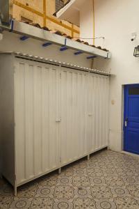 a row of white doors in a room with a blue door at Saqray Hostel in Cusco