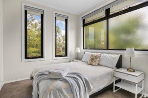 a bedroom with a bed and two windows at New Comfort house near Box Hill in Nunawading