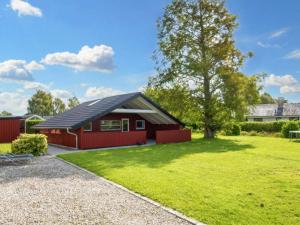 a red house with a black roof and a green yard at Holiday home Sydals LXXXIX in Neder Lysabild