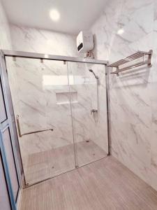 La salle de bains est pourvue d'une douche avec une porte en verre. dans l'établissement Binbaba Homestay - Grand Maganda, à Batam Center