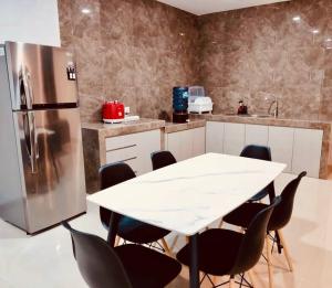 a kitchen with a table and a stainless steel refrigerator at Binbaba Homestay - Grand Maganda in Batam Center