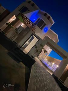 uma grande casa branca com luzes azuis em شاليه العماريه em Yanbu Al Bahr