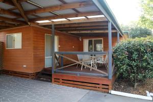 a screened in porch of a house with a table and chairs at NRMA Ocean Beach Holiday Resort in Umina