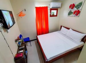 a bedroom with a bed with a red curtain and a television at Downtown Suites CDO in Cagayan de Oro