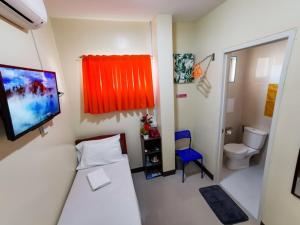 a small room with a bed and a toilet at Downtown Suites CDO in Cagayan de Oro