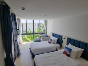a hotel room with two beds and a window at Oceanami Resort Sea View in Long Hai
