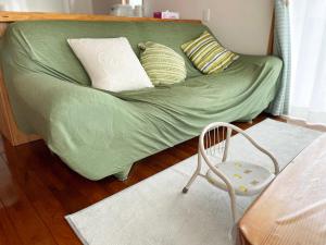 una cama verde con almohadas y una silla en una habitación en 憩いの場　ただいま〜, en Nago