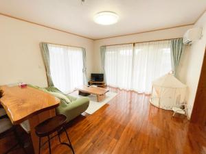 a living room with a green couch and a table at 憩いの場　ただいま〜 in Nago