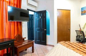 um quarto com uma cama, uma televisão e uma porta em Room in Guest room - Suite 2 Vena Close to buses and supermakets em Puerto Vallarta