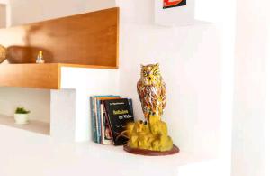 uma estátua de coruja sentada numa prateleira ao lado de livros em Room in Guest room - Suite 2 Vena Close to buses and supermakets em Puerto Vallarta