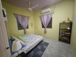 a bedroom with a bed and two windows at Umar's Tiny House in Kampong Kemaman