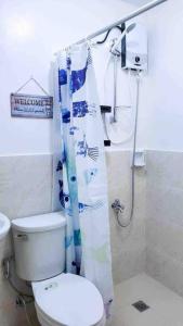 a bathroom with a toilet and a shower curtain at Urban oasis40 in Talisay