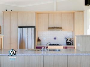 een keuken met houten kasten en een gootsteen bij Architect Designed Beach House with Sweeping Views in Goolwa South