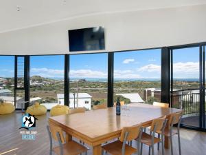 een eetkamer met een tafel, stoelen en ramen bij Architect Designed Beach House with Sweeping Views in Goolwa South