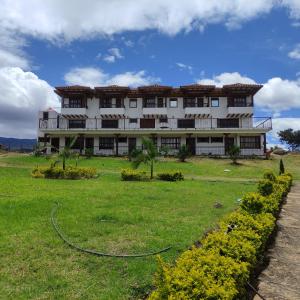 een groot wit gebouw met een groen veld ervoor bij Hotel Artemisa in Sutamarchán