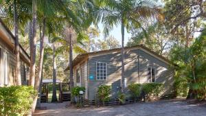 a small house with palm trees in front of it at NRMA Ocean Beach Holiday Resort in Umina