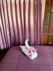 een paars bed met een olifantvormige handdoek met bloemen erop bij The Best Garden resort in Sichon