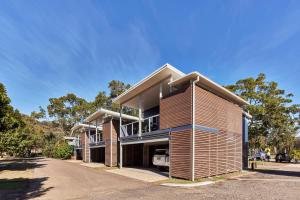 Une grande maison avec balcon est située dans une rue. dans l'établissement NRMA Ocean Beach Holiday Resort, à Umina