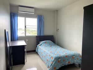 1 dormitorio con 1 cama con edredón azul y ventana en House near Suvarnabhumi Airport, en Ban Hua Takhe