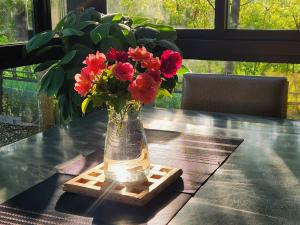 un jarrón con flores rojas sentado en una mesa en Najima B&B en Jian